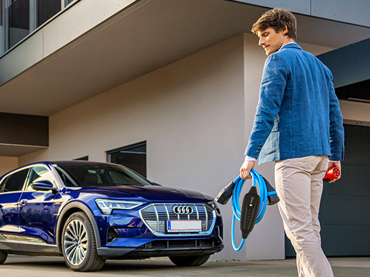 Osoba hoda prema automobilu s kabelom u ruci