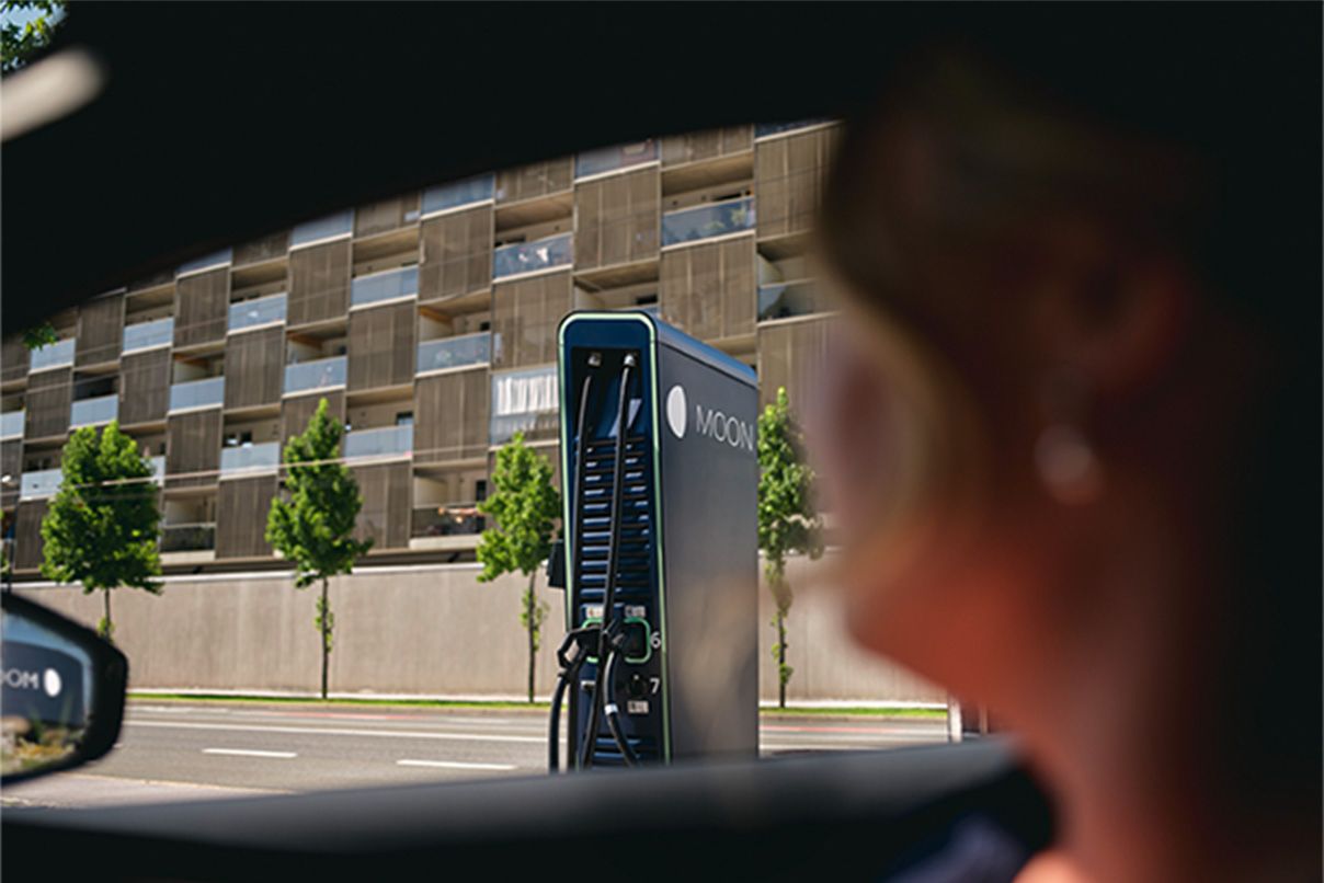 Osoba sjedi u autu s punjačem u pozadini