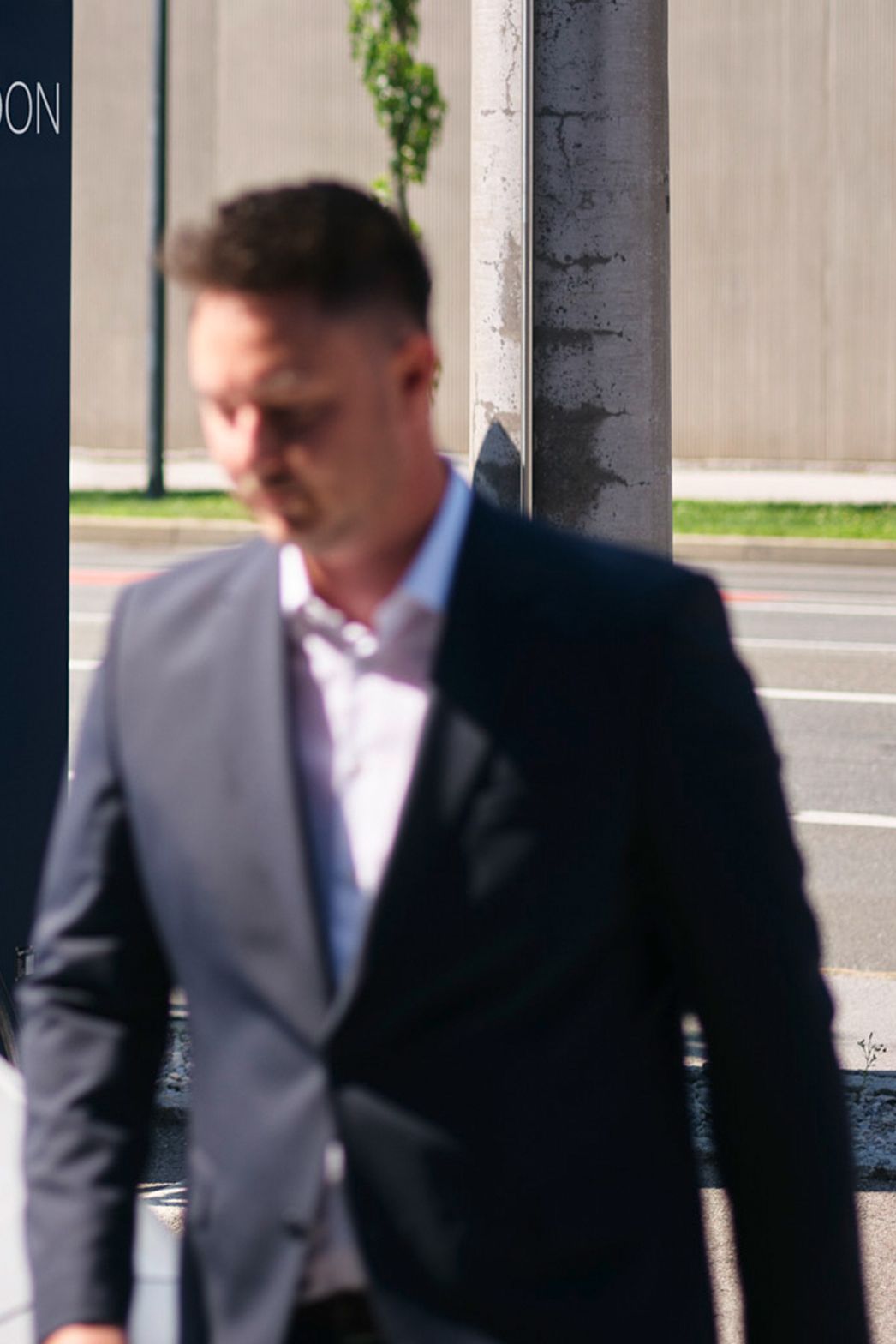 Muškarac hoda ispred automobila ispred stanice za punjenje