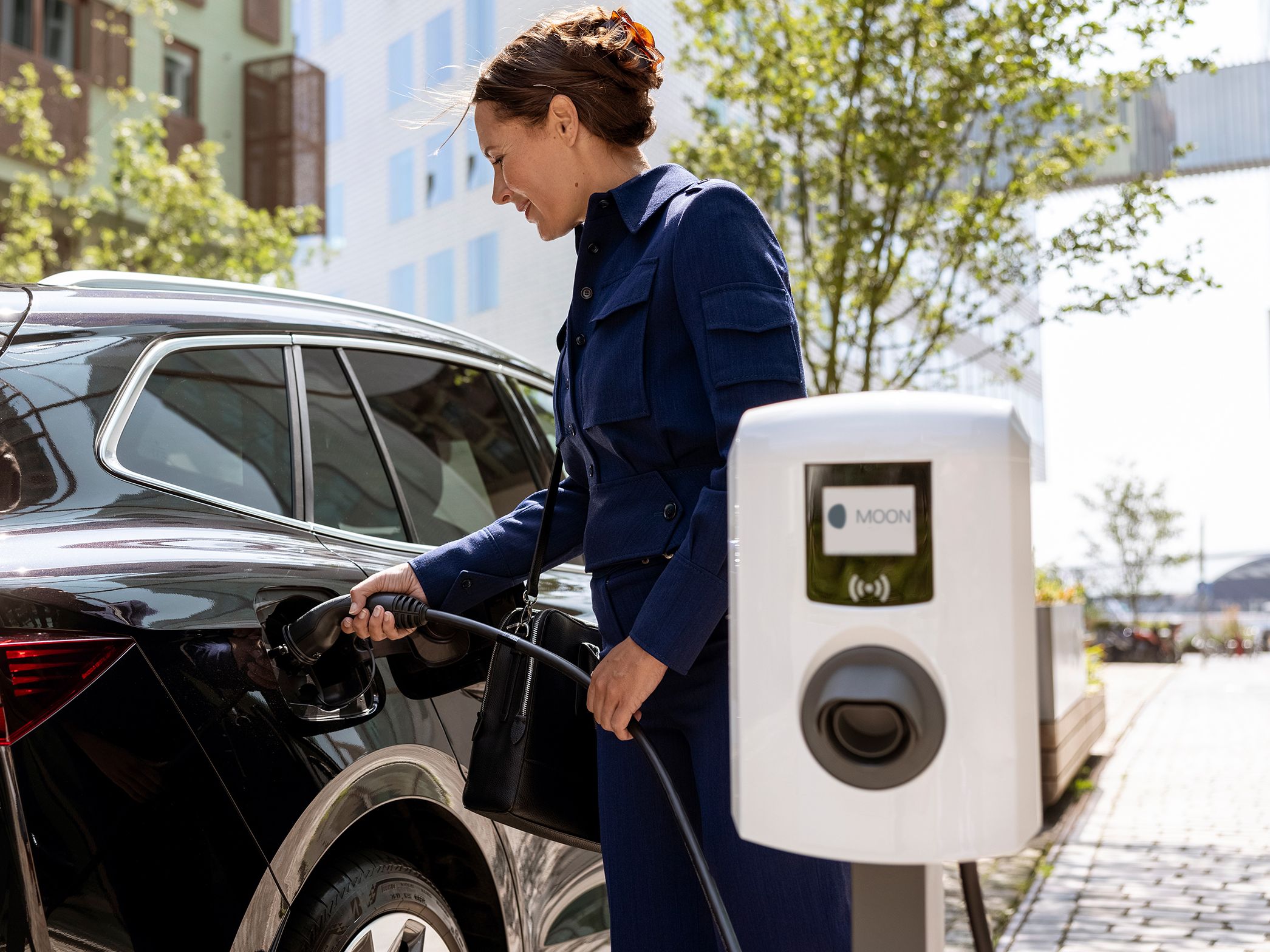 Žena ubacuje slavinu u automobil s zidnom kutijom u prvom planu