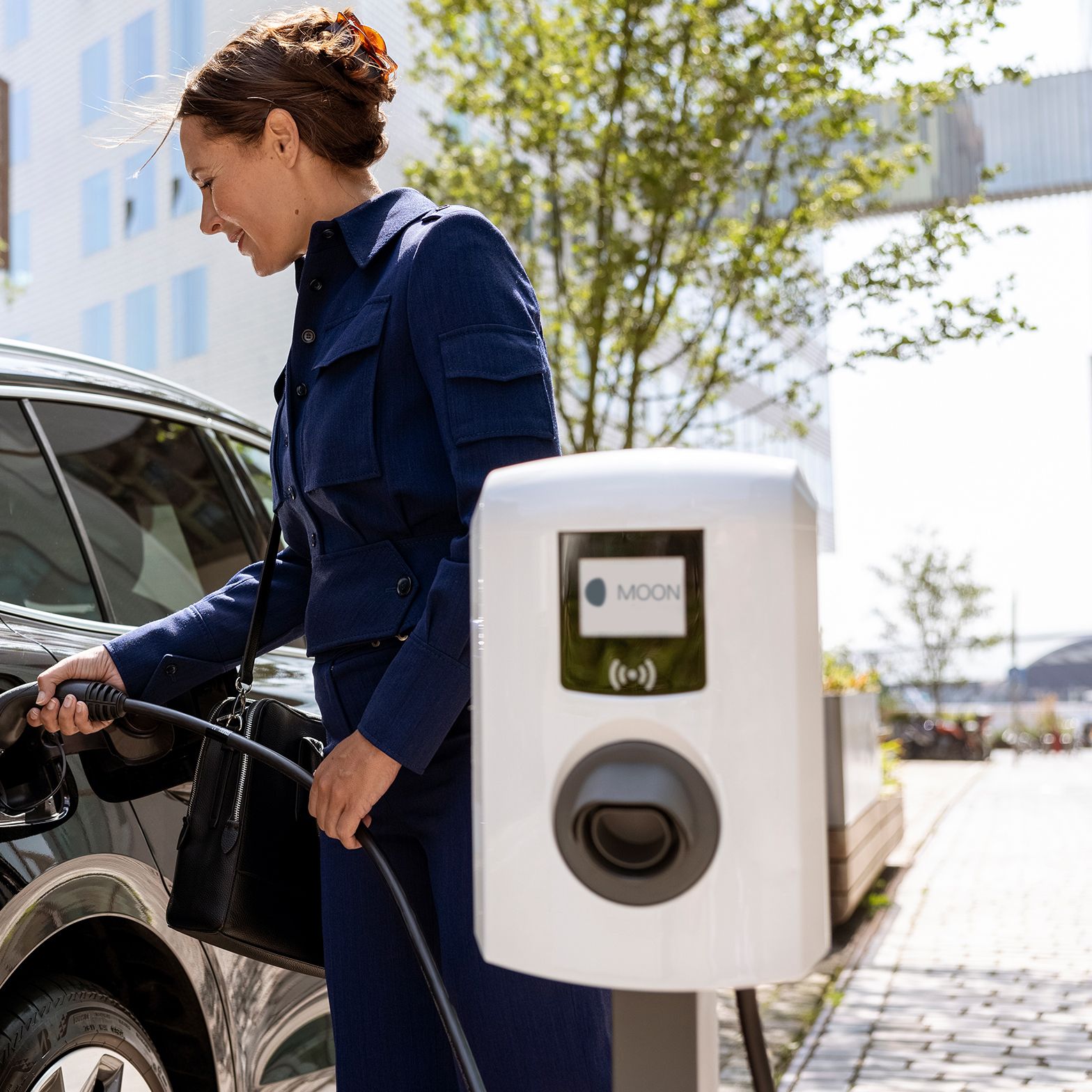 Žena ubacuje slavinu u automobil s zidnom kutijom u prvom planu