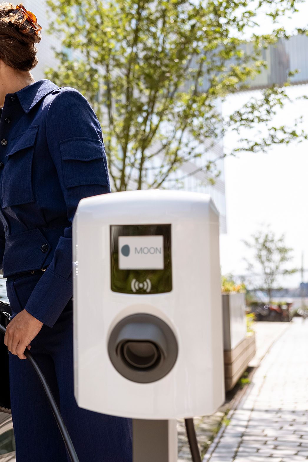 Žena ubacuje slavinu u automobil s zidnom kutijom u prvom planu