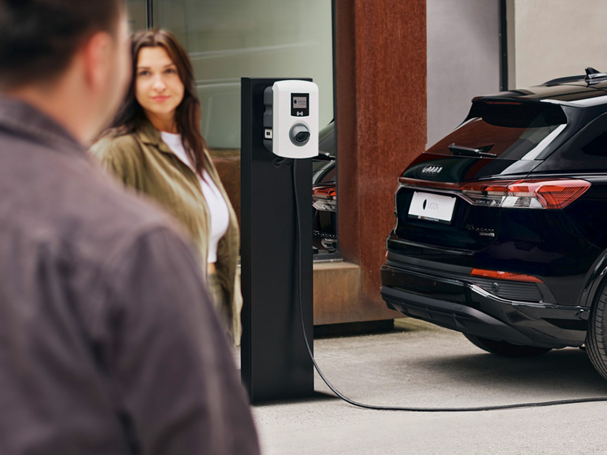 Automobil se puni na punionici s dvije osobe u prvom planu