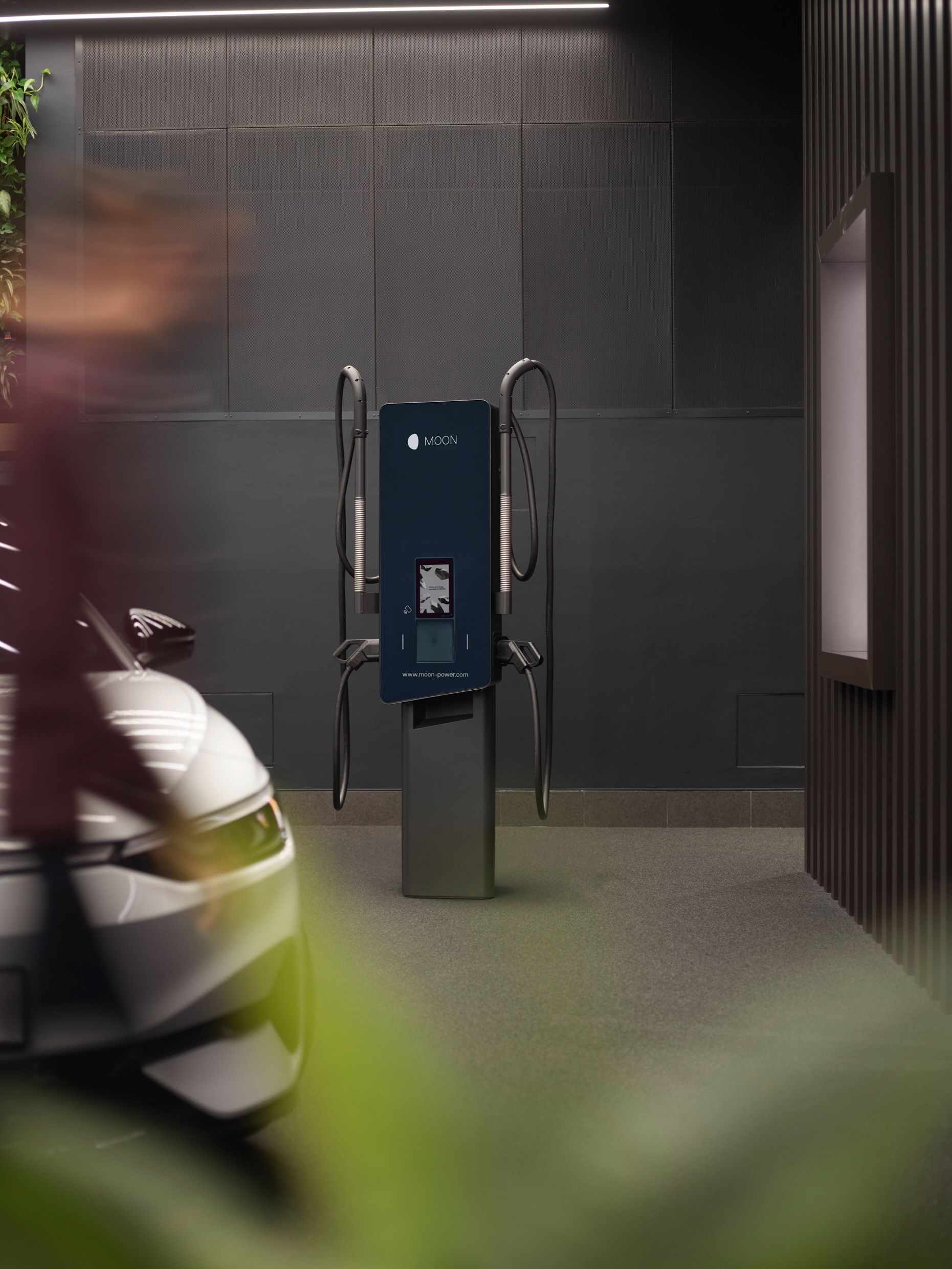 Punionica u sobi sa sivim zidovima i automobilom u prvom planu