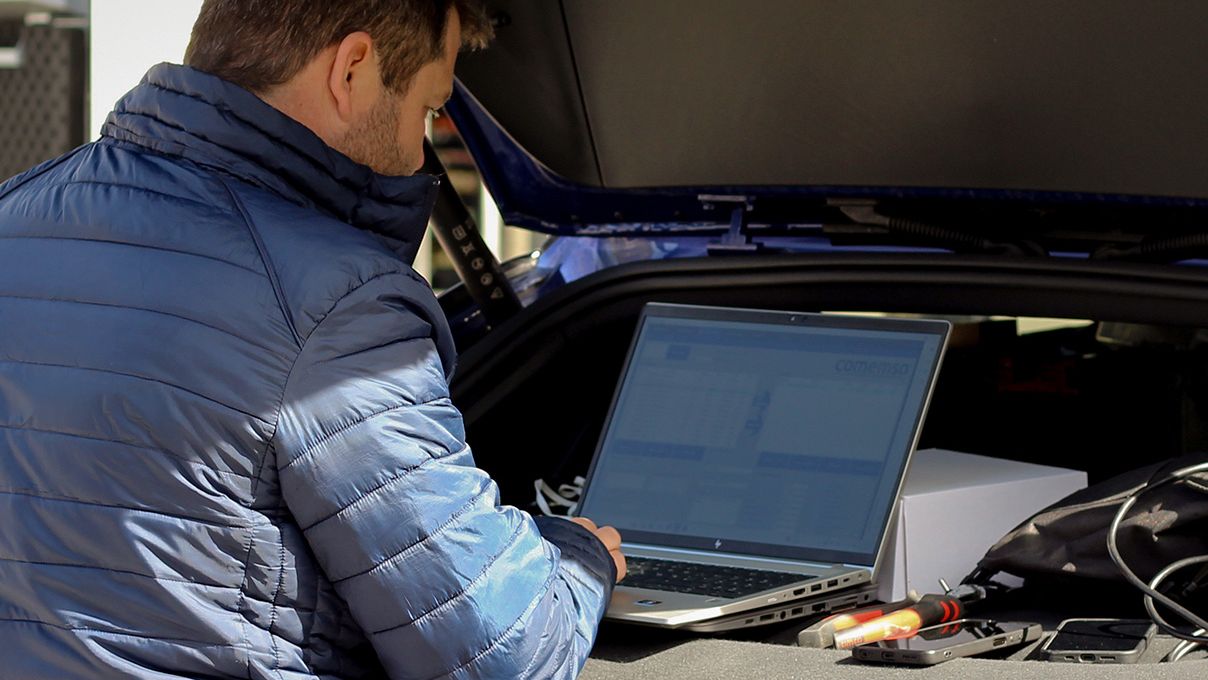 Čovjek s laptopom stoji na poklopcu prtljažnika