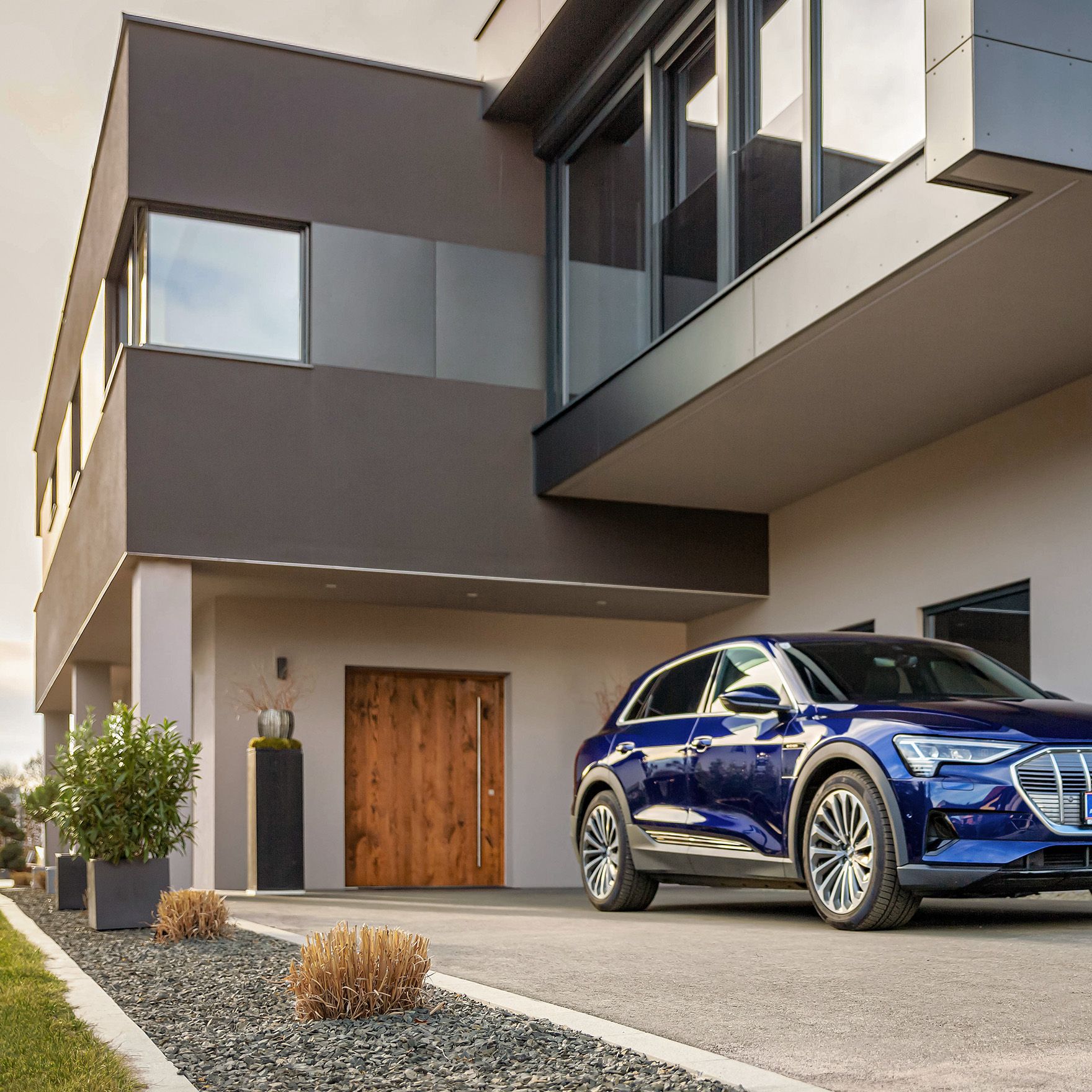 Muškarac hoda prema automobilu blizu kuće s kabelom u ruci