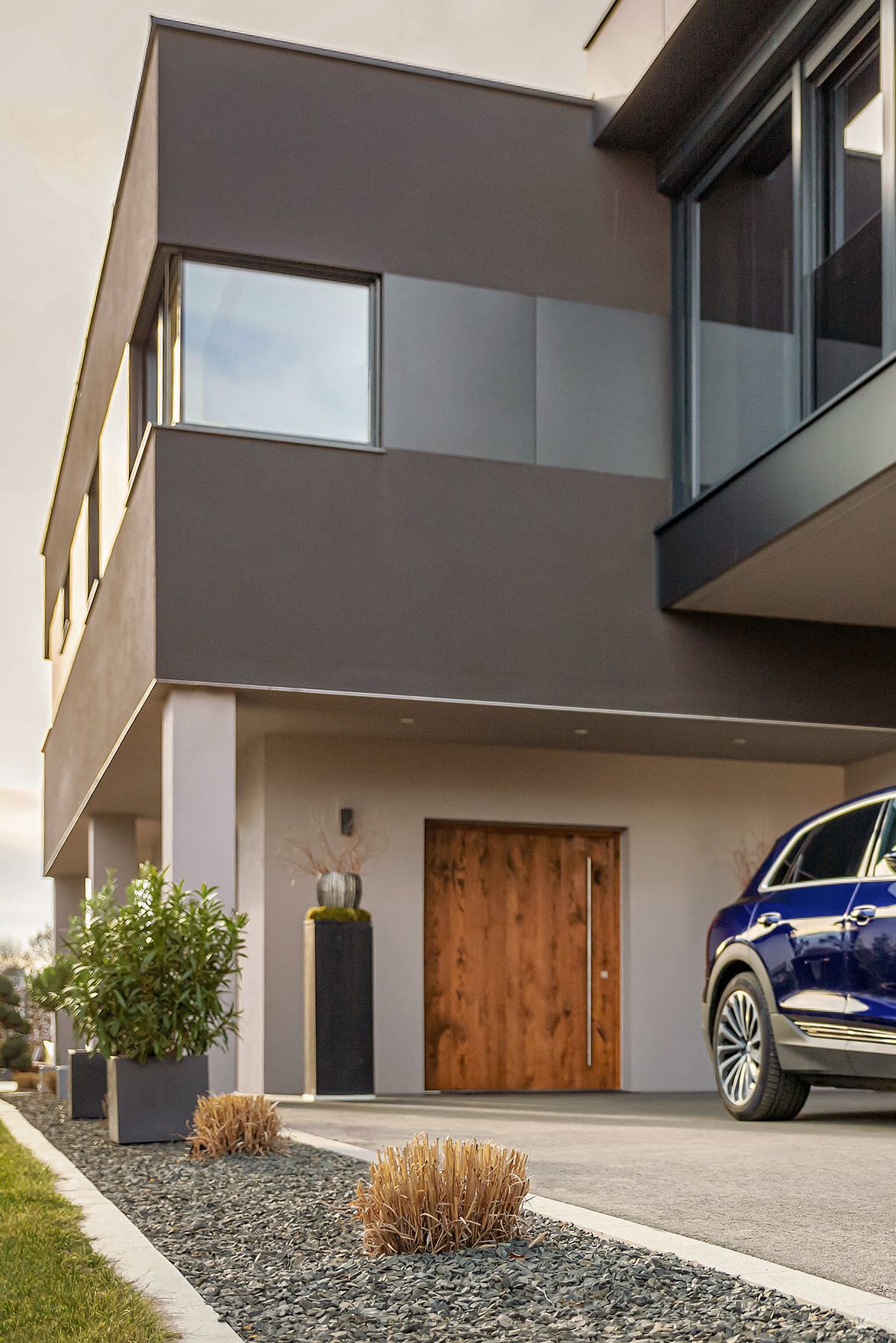 Muškarac hoda prema automobilu blizu kuće s kabelom u ruci