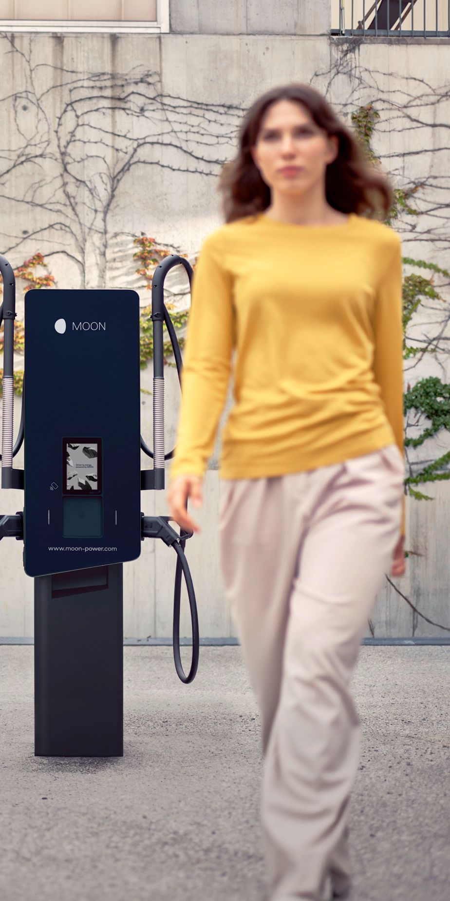 Žena hoda ispred punionice s automobilom u pozadini