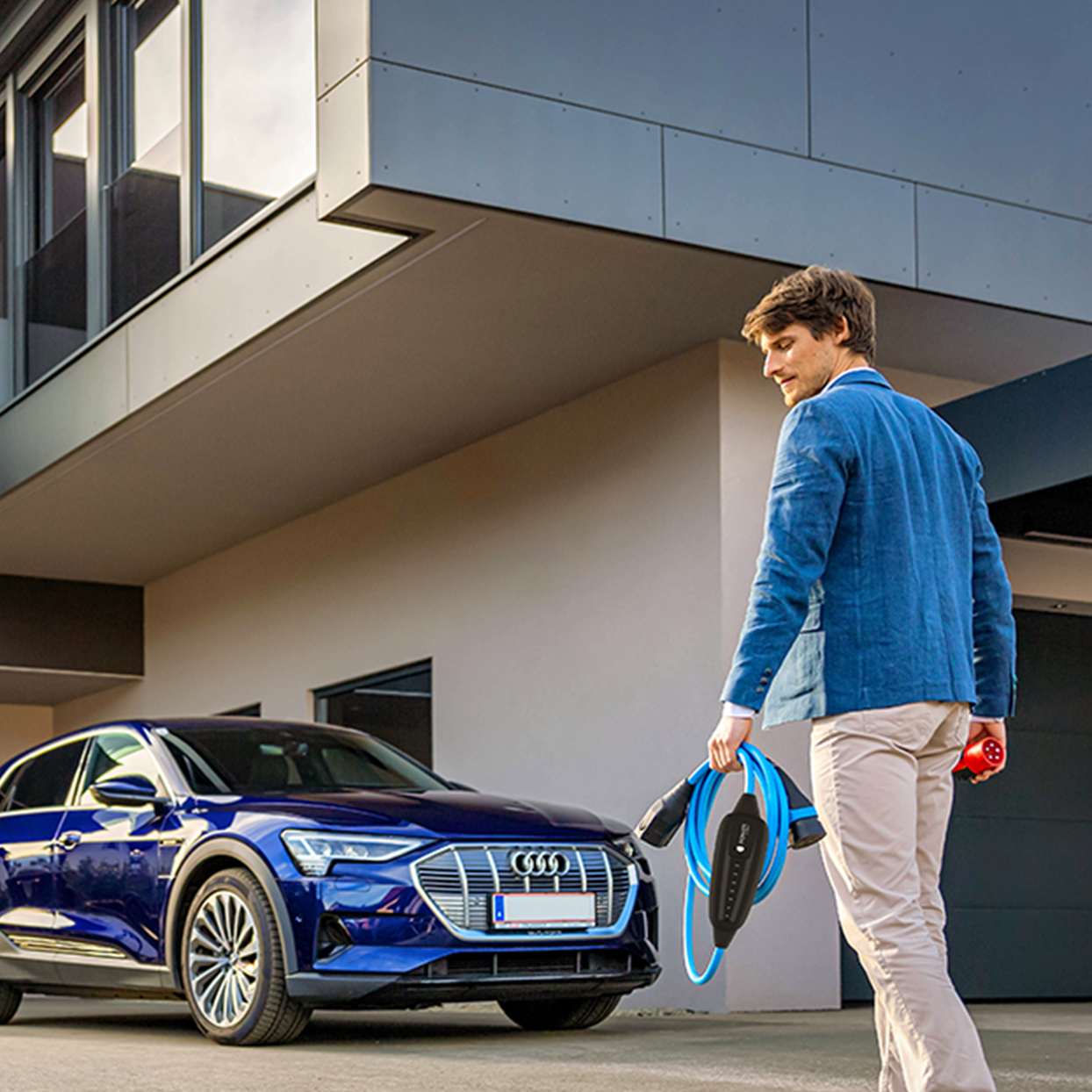 Osoba hoda prema automobilu s kabelom u ruci