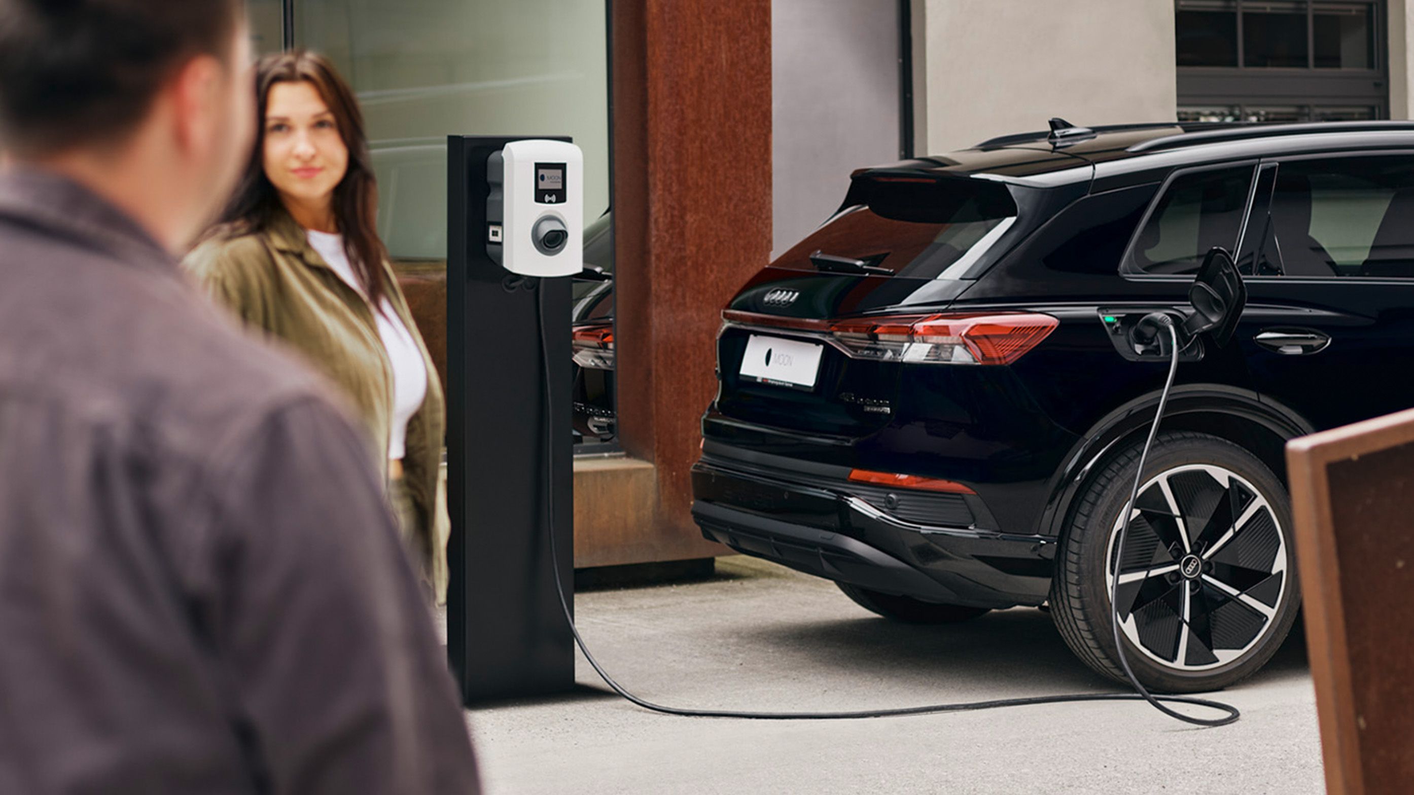 Automobil se puni na punionici s dvije osobe u prvom planu