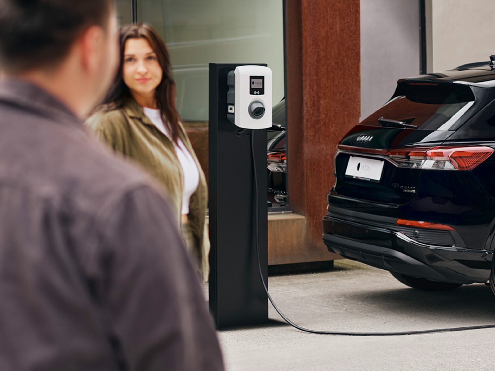 Automobil se puni na punionici s dvije osobe u prvom planu