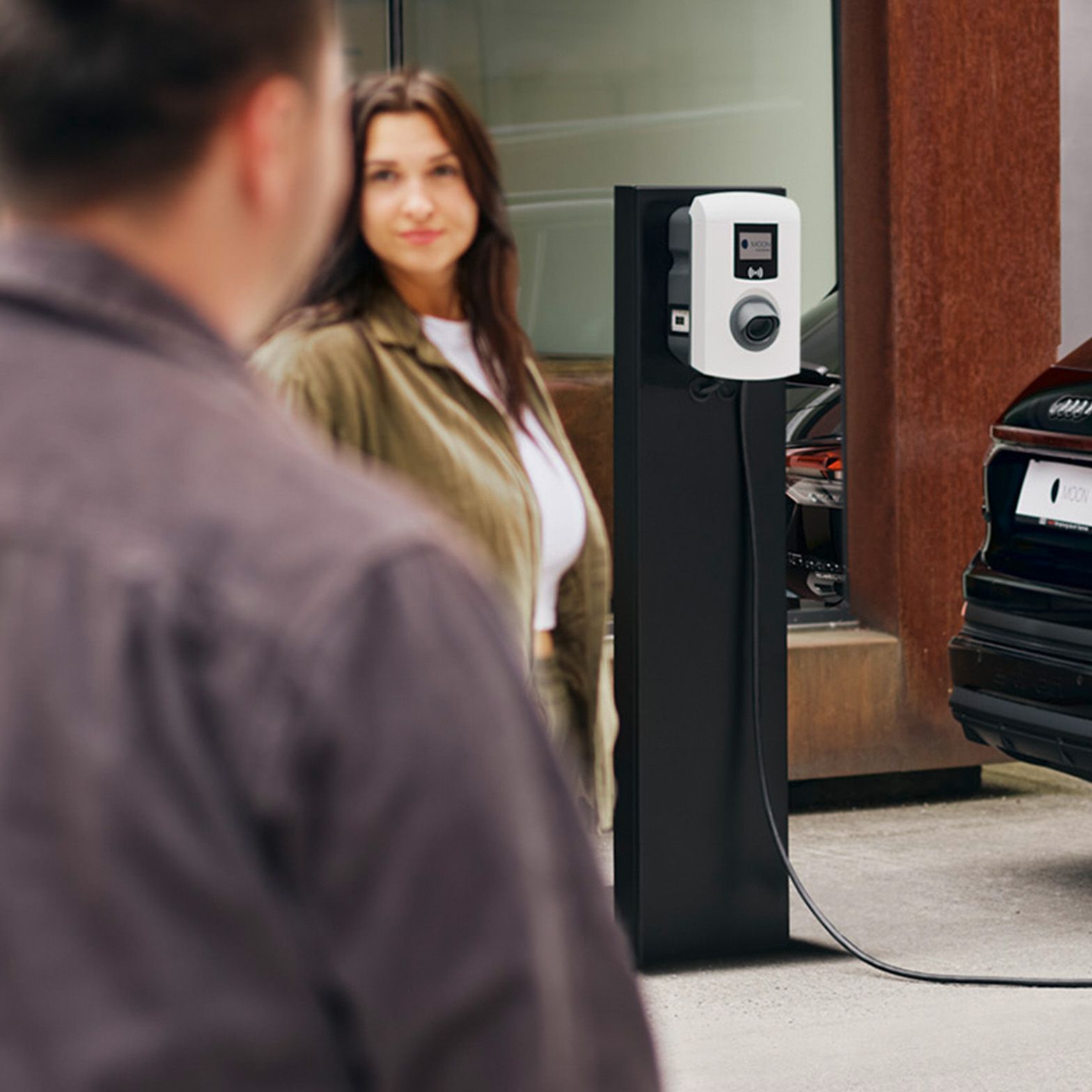 Automobil se puni na punionici s dvije osobe u prvom planu